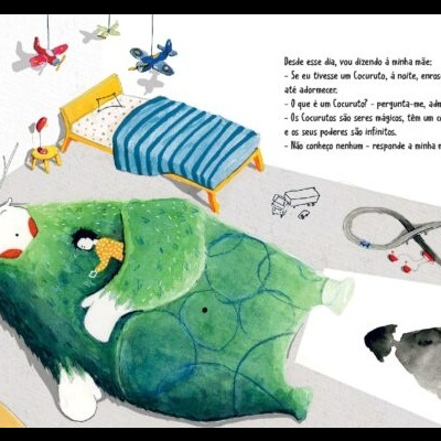 Criança a dormir embrulhada numa colcha verde com padrão circular, rodeada por brinquedos e texto em português numa parede branca.