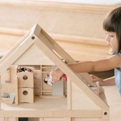 Casinha de madeira clara para brincar com móveis e criança a brincar