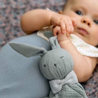 Bebé com body cinza segurando peluche de coelho cinzento