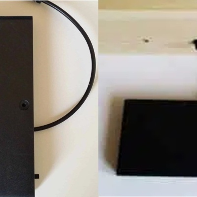 Carregador portátil preto com cabo USB em superfície branca e parede de madeira