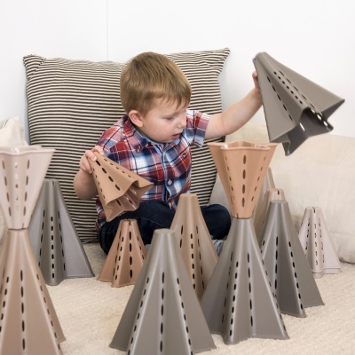 Criança a brincar com estruturas triangulares de plástico em sofá com almofadas