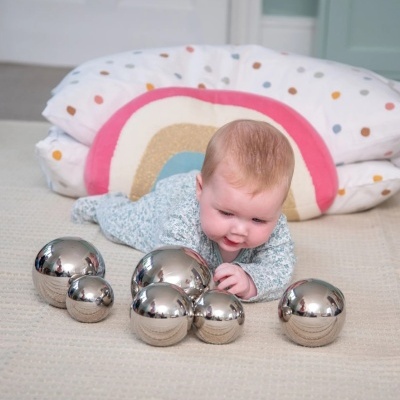Bebé a brincar com bolas metálicas refletoras sobre um tapete