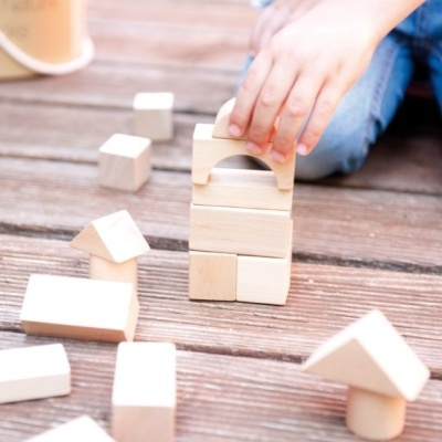 Blocos de madeira naturais geométricos e mão infantil a montar