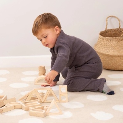 Criança a brincar com blocos de madeira no chão sobre tapete com padrão