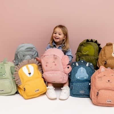 Mochilas infantis coloridas em peluche com padrões de animais, exibidas com uma criança sorridente no meio