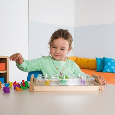 Criança a jogar com tabuleiro de madeira e peças coloridas