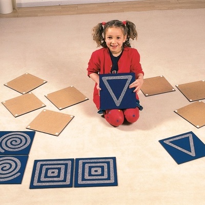 Criança com quadrados azuis e de cartão com padrões geométricos no chão