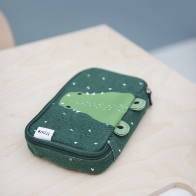 Bolsa em tecido verde escuro com padrão branco e aplicação decorativa, sobre mesa de madeira clara.