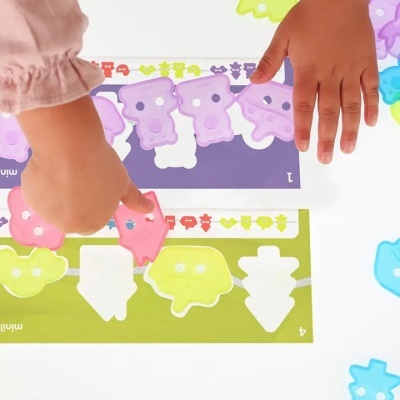 Criança a brincar com peças plásticas coloridas e cartelas numeradas coloridas.