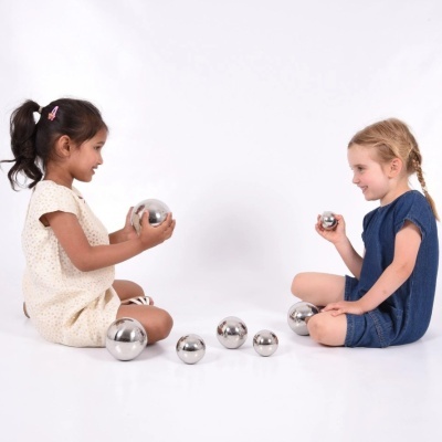 Duas crianças sentadas segurando bolas metálicas prateadas de vários tamanhos.