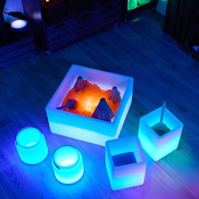 Conjunto de luminárias decorativas brancas translúcidas com luzes LED azuis e laranja em chão de madeira