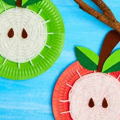 Dois círculos coloridos imitando maçãs com fios e papel sobre fundo azul claro