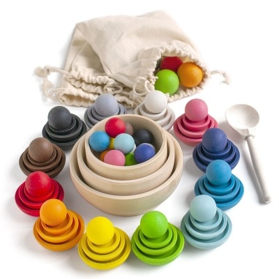 Brinquedos de madeira colorida com tigelas aninhadas, bolas, cones empilháveis, colher de madeira e saco de pano