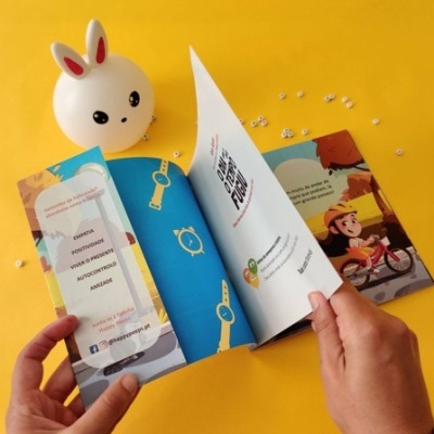 Livro infantil colorido aberto, mãos seguram páginas, luz decorativa de coelho