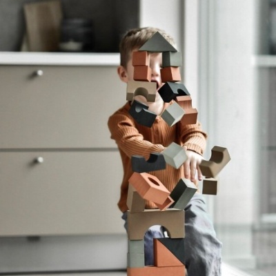 Criança a empilhar blocos de madeira coloridos