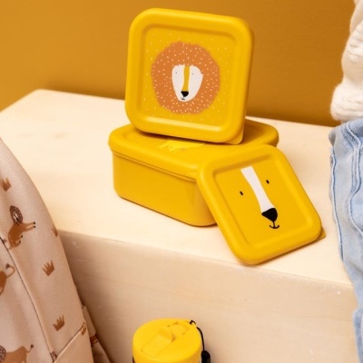 Caixas de plástico amarelas com tampas decoradas com faces de leões e garrafa térmica amarela numa superfície clara.