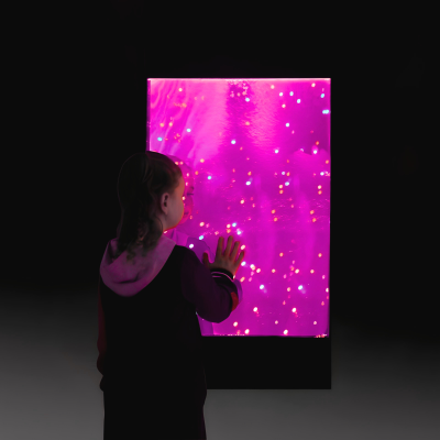 Menina em ambiente escuro toca painel luminoso rosa com luzes coloridas
