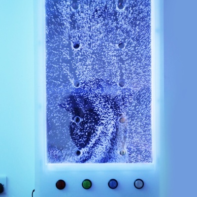 Painel electrónico com luzes e botões coloridos fixado numa parede azul