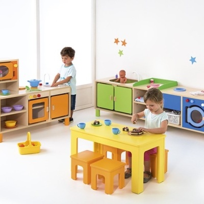 Crianças brincam com brinquedos de cozinha em mobiliário infantil colorido