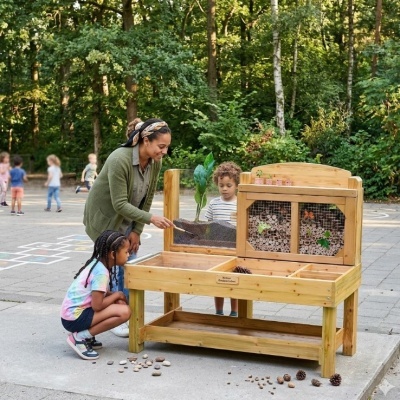 Banco de madeira para atividades educativas ao ar livre com caixas de plantação e elementos naturais