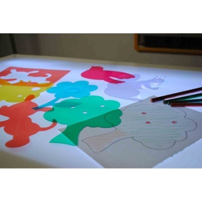 Formas de plástico colorido translúcido e desenho de mão com lápis de cor sobre uma superfície iluminada