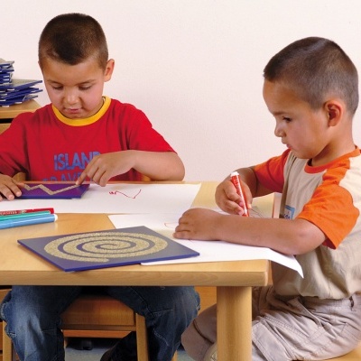 Duas crianças desenhando à mesa com canetas coloridas