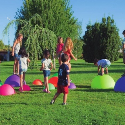 Crianças a brincar em estruturas semi-esféricas coloridas num parque ao ar livre