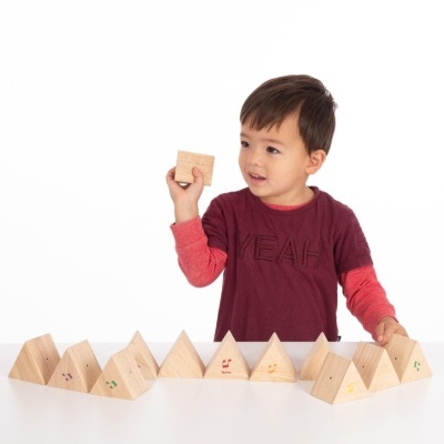 Criança com camisola segurando bloco de madeira com blocos triangulares à frente