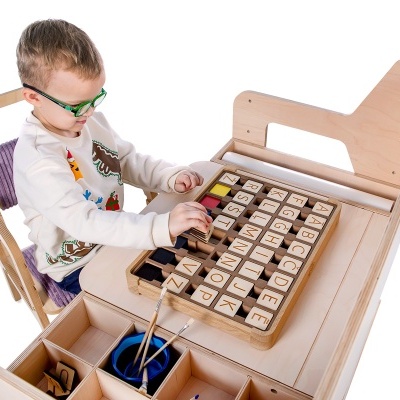 Menino a brincar com tabuleiro de letras e números em madeira clara