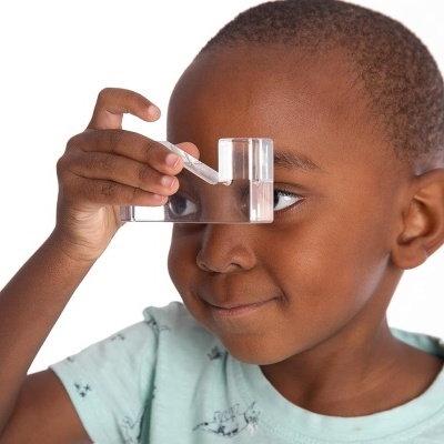 Menino segurando lupa retangular transparente perto do olho