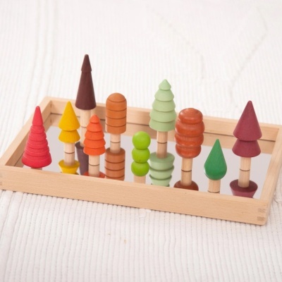 Árvores de madeira coloridas numa bandeja de espelho