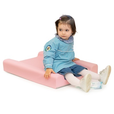 Criança sentada num trocador de bebé rosa claro com bata azul e calças azuis