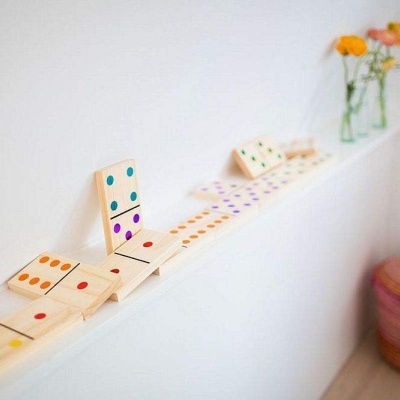 Peças de dominó de madeira com pontos coloridos numa prateleira branca