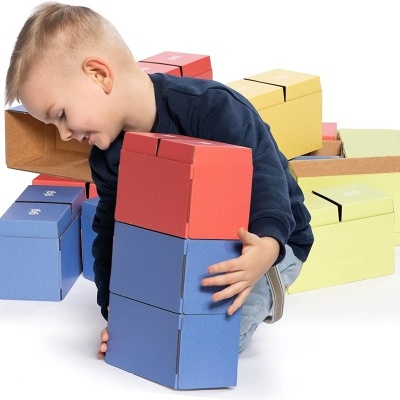 Menino a empilhar caixas coloridas de papelão