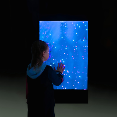 Criança vendo painel iluminado com luzes azuis e pontos de luz cor-de-rosa