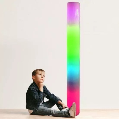 Menino sentado junto a cilindro colorido com padrão em gradiente de rosa, azul, verde e roxo