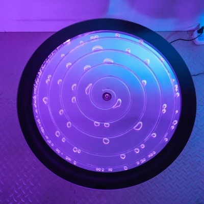 Luz decorativa circular com padrão espiral iluminada em tons roxos e azuis