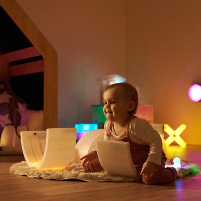 Bebé a brincar com luzes coloridas num ambiente interior acolhedor