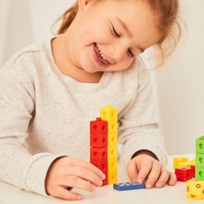 Criança a brincar com blocos de construção coloridos numa mesa branca