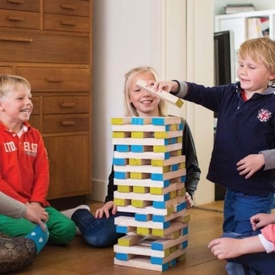 Crianças a jogar torre de blocos de madeira coloridos no chão de madeira