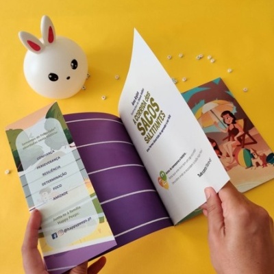 Lâmpada coelho branca e pequeno livro aberto com texto em português sobre fundo amarelo