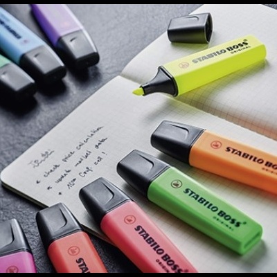 Marcadores fluorescentes STABILO BOSS e caderno aberto com escrita