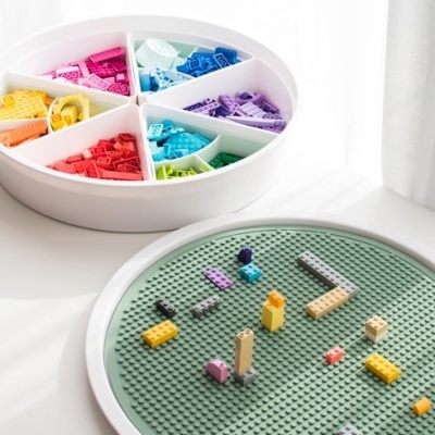 Bandeja branca com peças de construção coloridas e base verde para montar