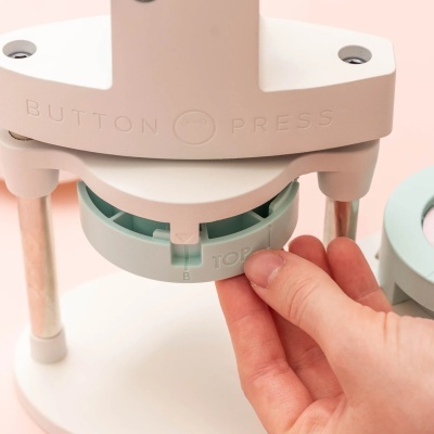 Máquina para fazer botões manual com detalhes em branco e verde água