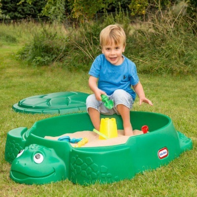 Caixa de areia infantil verde em forma de tartaruga com criança a brincar no jardim