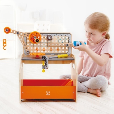 Bancada de trabalho infantil com ferramentas e menina a brincar