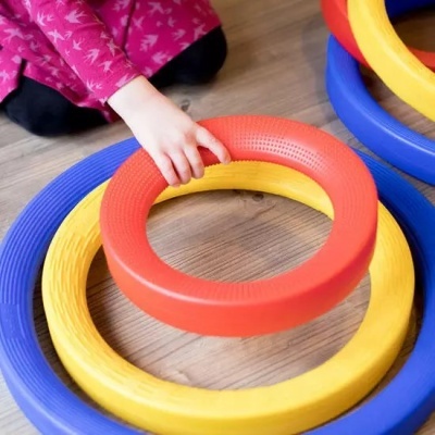 Brinquedo anel colorido em plástico com criança a tocar num dos anéis.