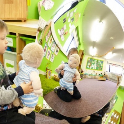 Criança a segurar boneco de pelúcia refletido em espelho convexo