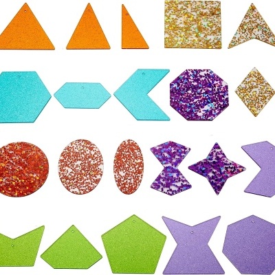 Pendentes de acrílico coloridos em várias formas geométricas e cores, com glitter e acabamento liso sobre fundo branco.