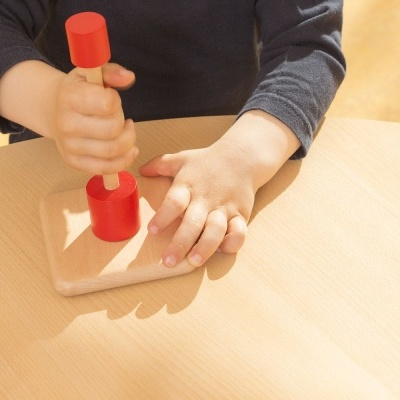 Brinquedo educativo de madeira com peças vermelhas em mesa clara